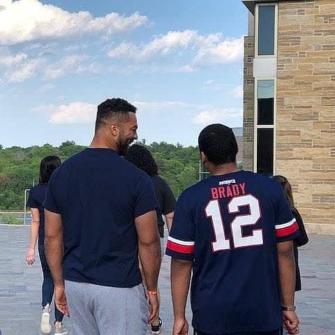 Two people face away from the camera laughing, one shirt says "Brady 12" on the back.