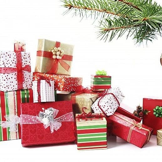 Photo of wrapped gifts under christmas tree with white background.