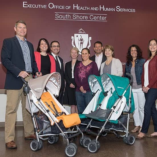 Group of people with empty strollers in front of sign for Executive Office of Health and Human Services - South Shore Center