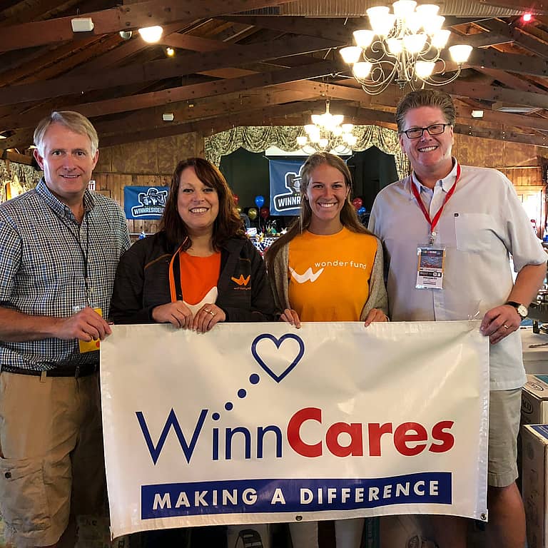 Group of 4 people holding a sign that says "Winn Cares"