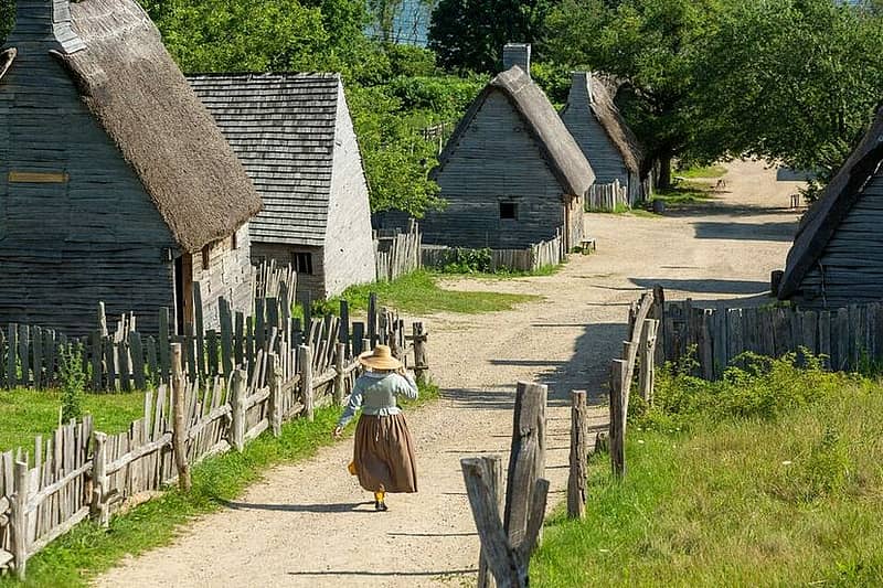 A woman in pilgrim attire walking through village