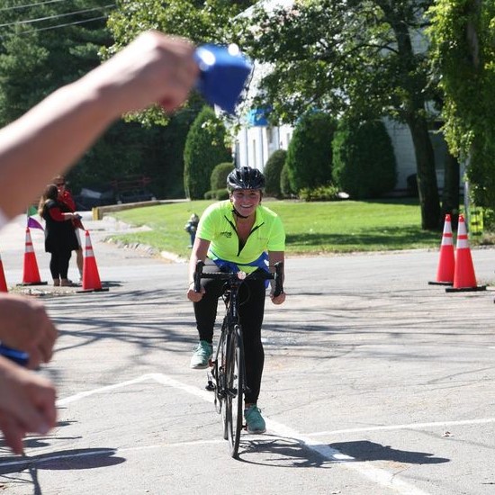 Woman in lime green shirt on bicycle smiling.