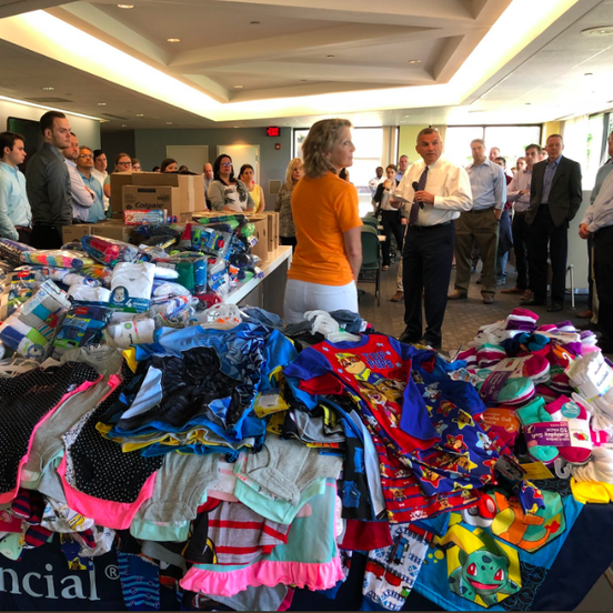 Large room full of tables piled with backpacks, and people.
