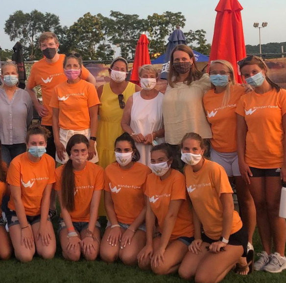 Group of young people posing for photo in orange shirts.